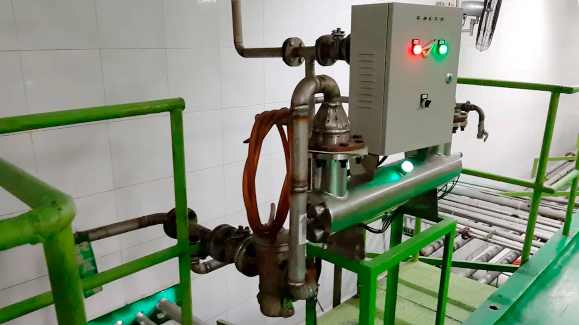 Técnico inspeccionando una planta de tratamiento de aguas residuales modular de color verde marca BIOMAX SYNERTECH, que incluye módulos de pretratamiento, decantación, DAF y oxidación avanzada. La planta está ubicada en un entorno industrial con techo alto y tuberías visibles. - ver más información